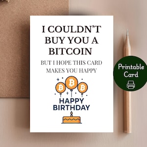 May include: A white birthday card with the text "I COULDN'T BUY YOU A BITCOIN BUT I HOPE THIS CARD MAKES YOU HAPPY". The card features orange Bitcoin balloons and a cake illustration. A pencil and a brown envelope are also visible.