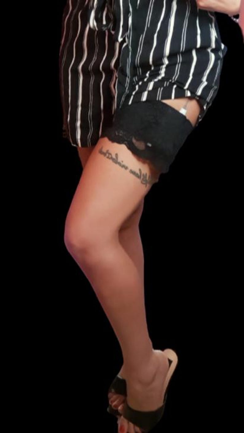 May include: Black and white striped shorts with a black lace garter. The shorts have a high waist and are made of a lightweight fabric. The garter is attached to the shorts with a button and loop.
