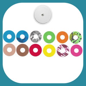 Può includere: Una varietà di cerchi adesivi colorati e con motivi per un dispositivo medico. I cerchi sono in tonalità di blu, verde, arancione, giallo, rosso, marrone e rosa. Alcuni cerchi hanno un motivo mimetico.