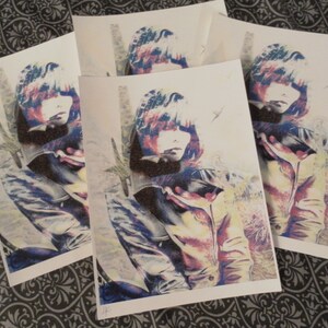 May include: A collection of art prints featuring a stylized portrait of a person with a jacket. The artwork uses a color palette of blue, red, and yellow, with a textured effect. The prints are arranged on a patterned surface.