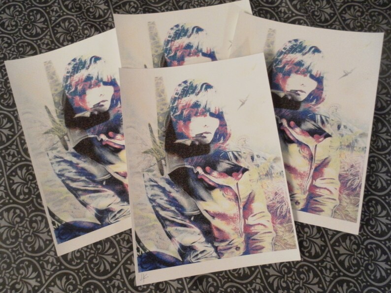 May include: A collection of art prints featuring a stylized portrait of a person with a jacket. The artwork uses a color palette of blue, red, and yellow, with a textured effect. The prints are arranged on a patterned surface.