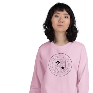 May include: Pale pink sweatshirt with a black circular emblem. The emblem reads "SATAN'S SCHOOL OF GAY COMMUNISM. FOUNDED 1871" around a crest with a pentagram, heart, and other symbols.