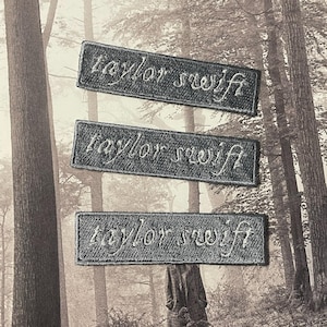 以下が含まれることがあります： 白で刺繍された「taylor swift」という文字が書かれた灰色の布のパッチが3つあります