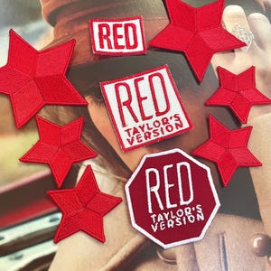 Pode incluir: Cinco patches vermelhos em forma de estrela e três patches retangulares vermelhos com texto branco. O texto nos patches diz "RED" e "RED TAYLOR'S VERSION".