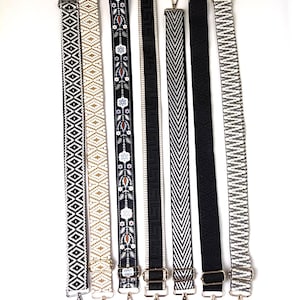 May include: Seven adjustable bag straps arranged vertically, featuring various patterns including black and white geometric diamonds, floral motifs, Greek key designs, chevron stripes, and solid black, all equipped with metal swivel lobster clasps.