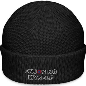 Puede incluir: Gorro negro de punto con un diseño bordado en blanco que dice "ENJOYING MYSELF" con un círculo rojo y azul en el medio de la palabra "ENJOYING".