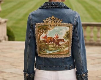 May include: A blue denim jacket featuring a large rectangular tapestry panel on the back depicting a fox hunting scene with riders on horseback. The jacket has a frayed dark blue tweed collar and matching frayed cuffs with gold buttons.