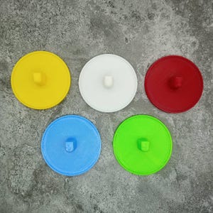 May include: Five round, flat, plastic discs in different colours: yellow, white, red, blue, and green. Each disc has a small hole in the centre.