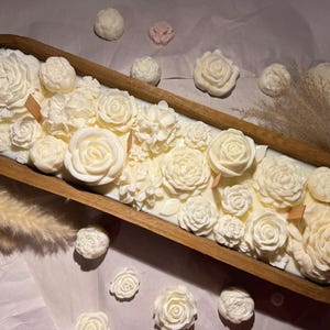 May include: A wooden bowl filled with a white floral arrangement candle. The candle is made of soy wax and has a natural wood wick. The bowl is made of natural wood and has a rustic finish.