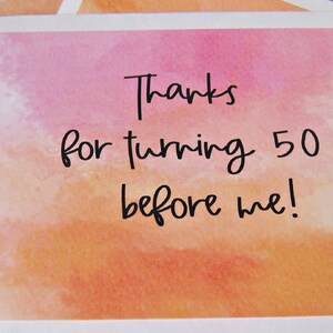 May include: A watercolor card with a pink and orange background. The card says "Thanks for turning 50 before me!"