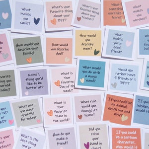 May include: A collection of colorful sticky notes with various questions written on them, such as "What made you laugh today?" and "What makes you smile?" Each note has a small heart illustration.