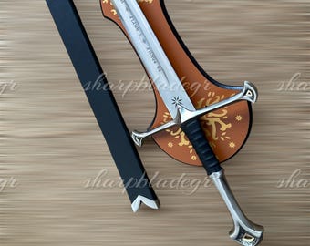 May include: A silver sword with a black handle and a brown leather scabbard with gold accents. The scabbard has the words "Valyrian Steel" and "Winter is Coming" inscribed on it.