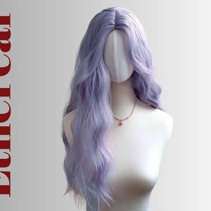 May include: A long, wavy lavender wig styled on a mannequin head. The wig has a natural-looking part and falls to the shoulders. A delicate pink necklace adorns the mannequin's neck. The word "Ethereal" is printed vertically in red.