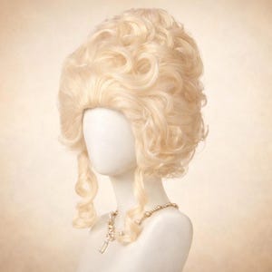 May include: A light blonde wig with voluminous curls and a high crown, styled in a classic historical fashion. The wig is displayed on a mannequin head, paired with a pearl necklace with a pendant.