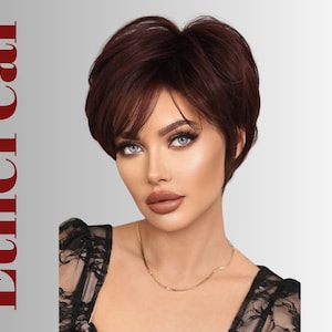 Op de afbeelding: Een vrouw met blauwe ogen en een kort, donkerroodblonde pruik. De pruik heeft een zijwaarts geveegde pony en is gestyled in een gelaagde pixie-cut. Het woord "Ethereal" staat in het rood aan de linkerkant. Ze draagt een zwarte kanten top en een gouden ketting.