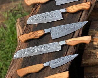 May include: Set of six kitchen knives with wooden handles and patterned steel blades. The knives are arranged on a wooden surface.