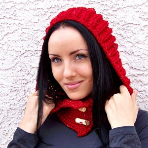 May include: A red knitted hooded scarf with wooden buttons. The scarf is worn by a person with long black hair.