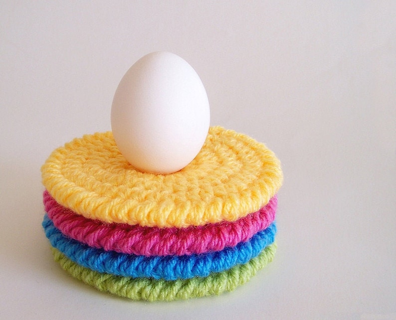 Round crochet coasters made with colorful worsted weight yarn, displayed on a white background. Easy, beginner-friendly crochet pattern for double-thick crochet coasters.