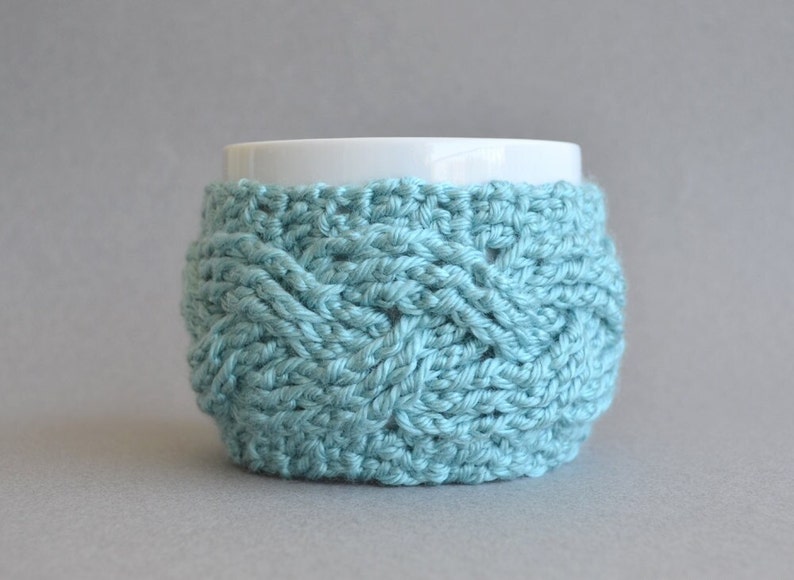 Easy crochet pattern for a cable crocheted cup cozy with a big button. This simple crocheting tutorial is a perfect gift to learn how to crochet cables.