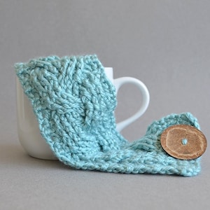 Easy crochet pattern for a cable crocheted cup cozy with a big button. This crocheting tutorial is a perfect gift to learn how to crochet cables.