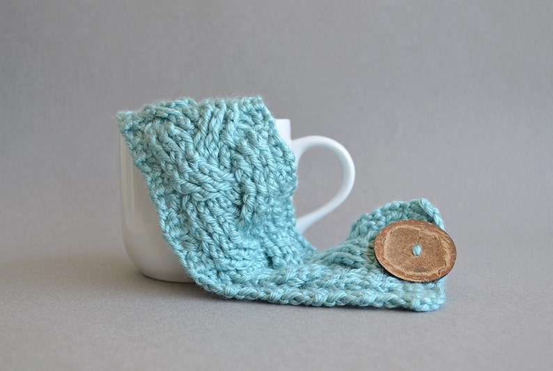 Easy crochet pattern for a cable crocheted cup cozy with a big button. This crocheting tutorial is a perfect gift to learn how to crochet cables.