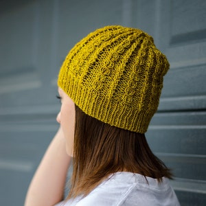 May include: A yellow knitted beanie with a cable knit pattern.