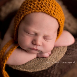 Baby wearing a classic knit bonnet. This is an easy knitting pattern for a baby hat with ties.