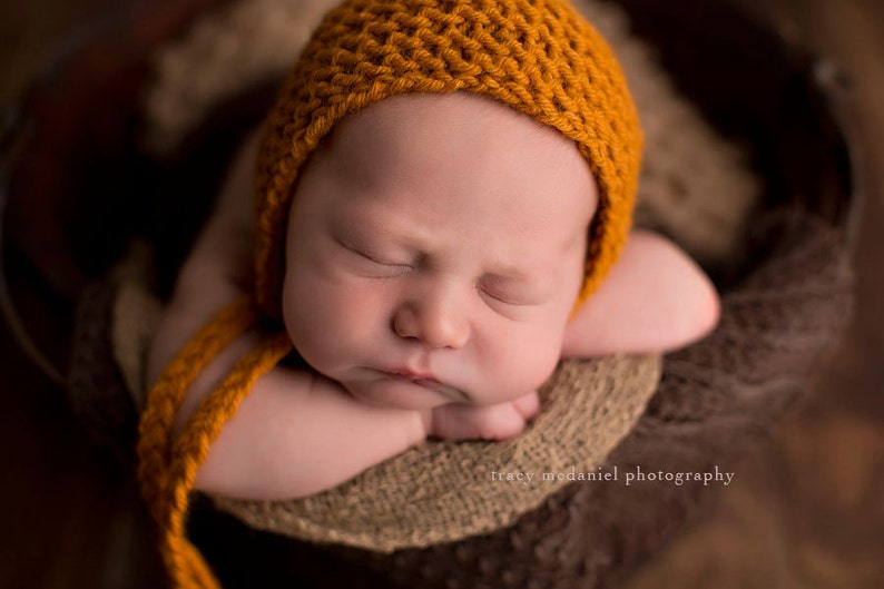 Baby wearing a classic knit bonnet. This is an easy knitting pattern for a baby hat with ties.