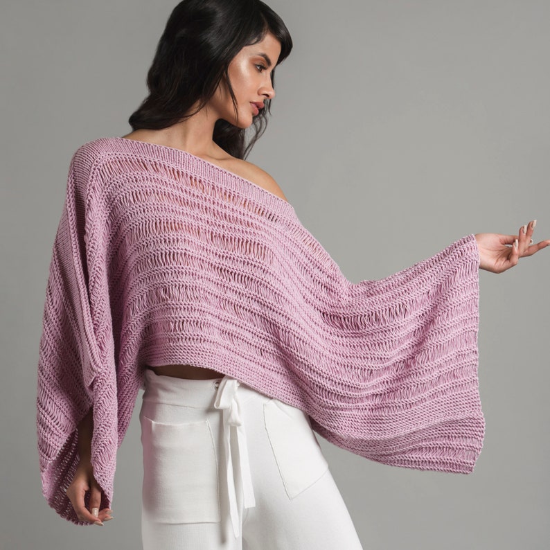 A young woman is wearing a light pink knit summer sweater, boatneck crop top with wide long sleeves. Aitana Sweater Top features stockinette, garter stitch, and three types of drop stitches. This listing is an easy knitting pattern, instant download PDF file.