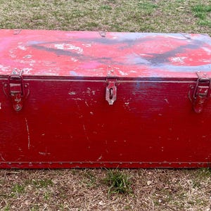 May include: A vintage red wooden storage chest with two metal clasps and a worn, distressed finish.