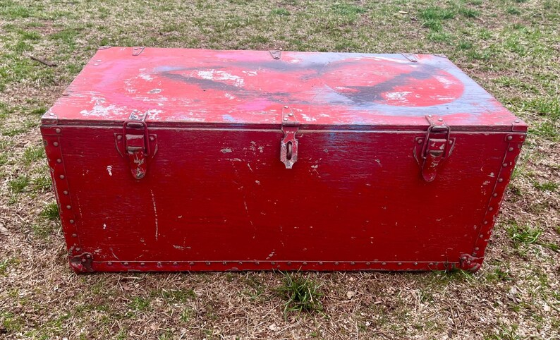 May include: A vintage red wooden storage chest with two metal clasps and a worn, distressed finish.
