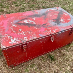May include: A red wooden storage chest with metal hardware and a distressed paint finish. The chest has a hinged lid and a metal handle on the side.