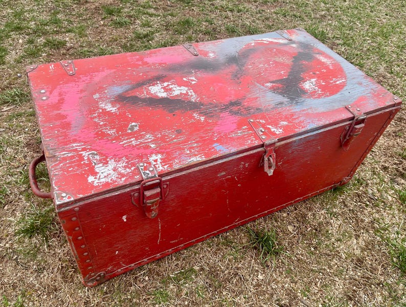 May include: A red wooden storage chest with metal hardware and a distressed paint finish. The chest has a hinged lid and a metal handle on the side.