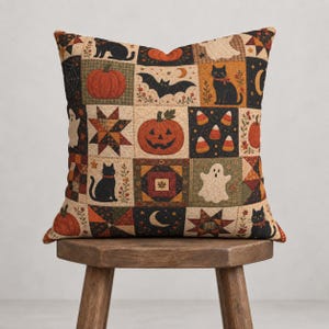 Puede incluir: Un cojín cuadrado con un diseño de patchwork que presenta ilustraciones temáticas de Halloween, incluyendo gatos negros, calabazas naranjas, linternas, fantasmas blancos, murciélagos, dulces, estrellas y lunas crecientes.