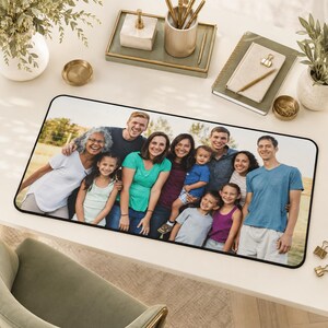 May include: A rectangular desk mat featuring a printed photograph of a large multi-generational family posing together outdoors. The family members are wearing casual clothing in various colors, including white, green, blue, and purple shirts.