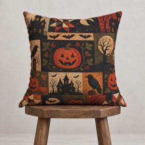 May include: A square throw pillow featuring a patchwork design with Halloween motifs including orange jack-o'-lanterns, black crows, silhouettes of haunted houses, bare trees, and flying bats against a dark background with quilted texture.