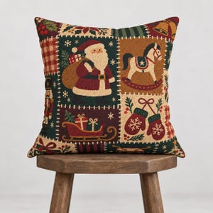 Könnte beinhalten: Ein quadratisches Zierkissen mit Patchwork-Design und Weihnachtsmotiven wie dem Weihnachtsmann, einem Schaukelpferd, einem Nussknacker, einem Schlitten mit Geschenken und Fäustlingen. Die Farbpalette umfasst Dunkelrot, Tannengrün und Beige.