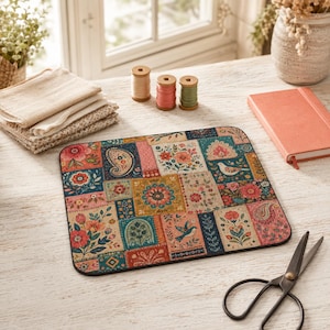 May include: A rectangular mouse pad featuring a colorful patchwork design with various floral patterns, paisley motifs, and illustrations of birds. The surface displays a mix of red, blue, yellow, and green hues arranged in distinct square and rectangular sections.