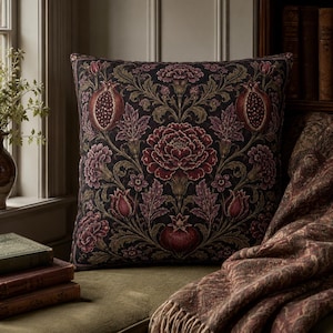May include: A square throw cushion featuring a dark black background with a symmetrical botanical pattern in shades of deep burgundy, muted red, and olive green. The design displays intricate illustrations of pomegranates, carnations, and leafy vines.