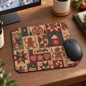 Op de afbeelding: Een rechthoekige muismat met een patchwork-stijl print met kerstmotieven zoals peperkoekmannetjes, zuurstokken, mokken cacao, sterren, hartjes en geometrische quiltpatronen in de kleuren rood, groen, crème en donkerblauw.