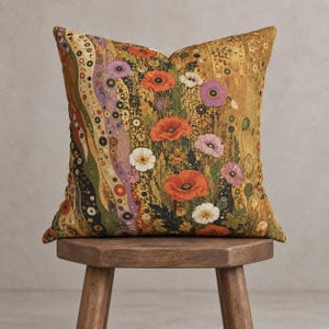 Peut inclure: Un coussin carré orné d'un motif floral vibrant composé de coquelicots orange, de marguerites blanches et de fleurs violettes sur un fond doré et vert olive, agrémenté de lignes ondulées verticales et de petits motifs circulaires.