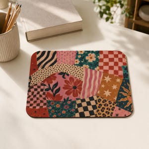 Può includere: Un tappetino per mouse rettangolare caratterizzato da un vivace design patchwork con vari motivi, tra cui fiori rosa, scacchi bianchi e neri, quadrati rossi e bianchi, stelle dorate, un motivo solare, stampa leopardata e strisce ondulate.