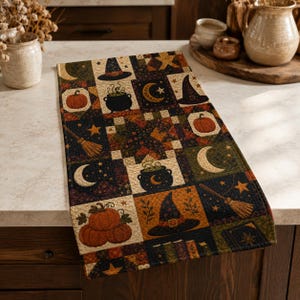 May include: A rectangular quilted table runner featuring a patchwork design with Halloween-themed motifs including orange pumpkins, black witch hats, bubbling cauldrons, crescent moons, stars, and brooms in a dark color palette of black, orange, and green.