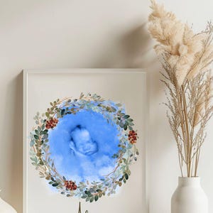 Peut inclure: Impression encadrée d'une échographie de bébé dans un cercle bleu aquarelle, entourée d'une couronne florale verte et rouge. Le nom "Alex" est écrit en cursive sous l'image, avec "first heartbeat" en dessous. L'impression est sur fond blanc.