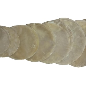 May include: A stack of thin, round, beige-colored food items, possibly tortillas or flatbreads, arranged in a slightly overlapping pattern. The items have a slightly translucent appearance.