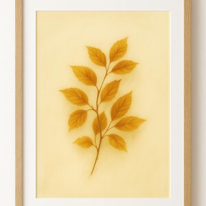 Può includere: Una stampa artistica incorniciata con un'illustrazione botanica di un ramo con foglie giallo dorato. L'opera d'arte è ambientata su uno sfondo giallo pallido e incorniciata in una cornice di legno chiaro con un passe-partout bianco.