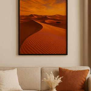 Può includere: Stampa incorniciata di un paesaggio desertico con dune di sabbia arancione sotto un cielo arancione. L'immagine è in una cornice nera e appesa sopra un divano beige con cuscini e un tavolino di legno. Un vaso con fiori secchi e una tazza sono sul tavolo.