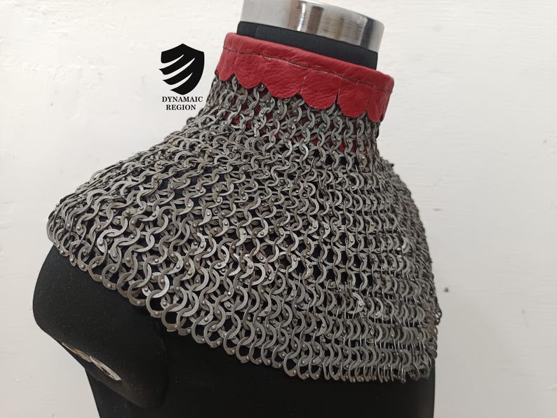 May include: A silver chainmail collar with a red leather trim. The collar is on a black mannequin.