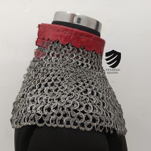 May include: A red leather collar with a chainmail neck guard. The collar has a scalloped edge and is fastened with buckles. The chainmail is made of small, interlocking metal rings.