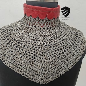May include: A silver chainmail collar with a red leather lining. The collar is on a mannequin and has a scalloped edge.